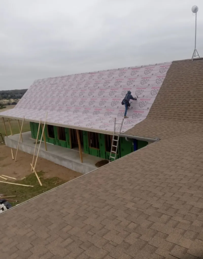 Worker preparing underlayment for a metal roof installation in Old Town